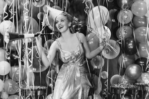 A retro party girl, in front of streamers and balloons