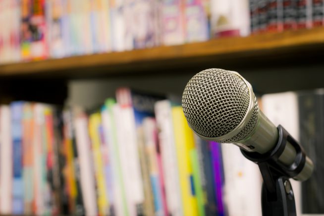 An image of an unmanned microphone in front of a row of books