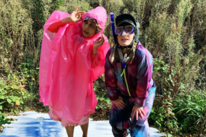 2 people standing in a puddle of water wearing bright coloured rain coats